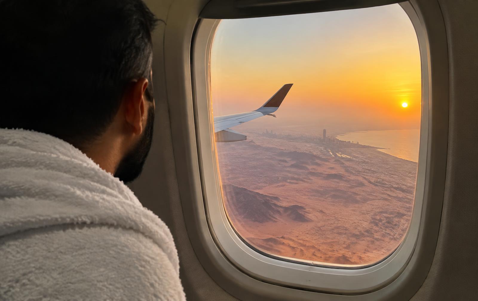 A pilgrim in ihram looking out of a plane window towards Jeddah